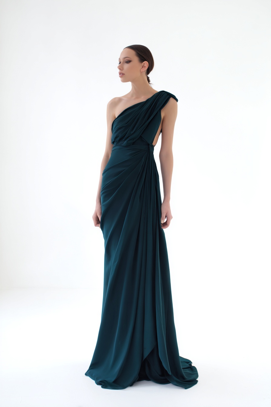 A modern minimalist evening dress, flowing silk fabric, deep emerald green, asymmetric neckline, floor-length, elegant draping, studio photography, white background